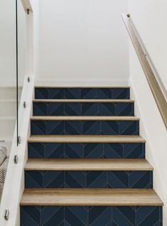 blue tiled stairs with wooden handrails in an otherwise white room, leading up to the second floor