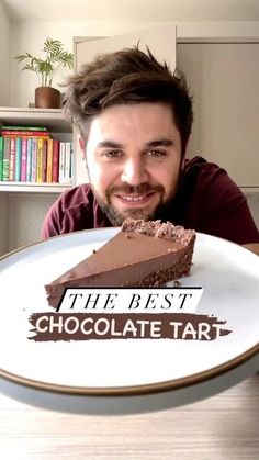 a man sitting in front of a plate with a piece of chocolate tart on it