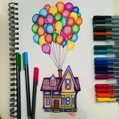 colored pencils are next to a drawing of a house with balloons