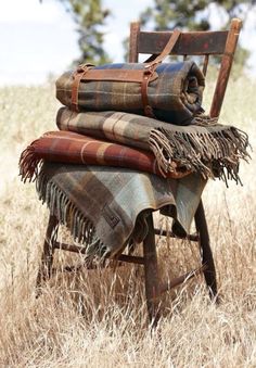 an old chair with blankets on it in the grass