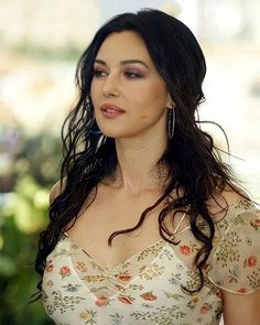 a woman with long dark hair wearing a floral top