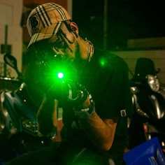 a man wearing a hat and holding a green light in his hand while sitting on a motorcycle