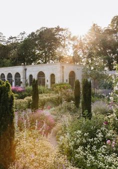 the sun shines through the trees and bushes in front of a building with arches