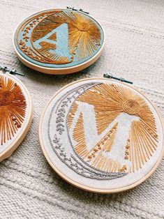 three hand embroidered hoops sitting on top of a white cloth covered floor next to each other