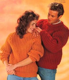 two people standing next to each other in front of an orange background wearing sweaters