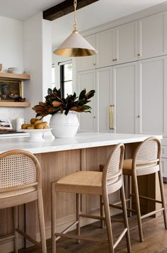 a kitchen island with two chairs and a potted plant on it's counter