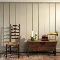 two wooden chairs sitting next to each other in front of a wall with white paneling