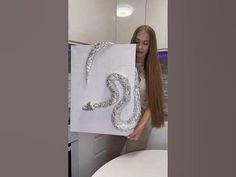 a woman is holding up a large white bag with silver sequins on it