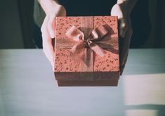 a person holding a small gift box with a bow