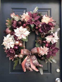 a wreath on the front door decorated with pink and purple flowers, baubles and ornaments