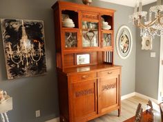 a wooden china cabinet sitting next to a chandelier