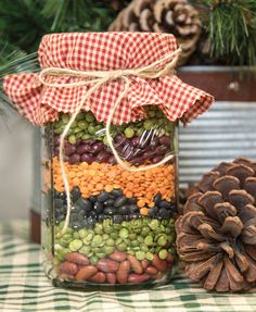 a jar filled with beans and pine cones on top of a table next to a pine cone