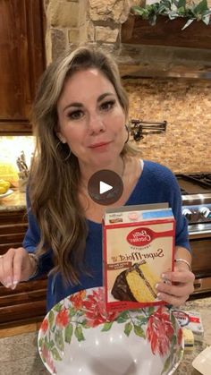 a woman holding up a box of cake mix