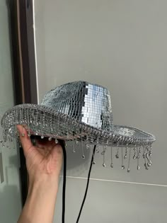 a person is holding up a silver hat