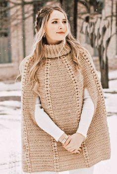 a woman standing in the snow with her hand on her head and wearing a sweater