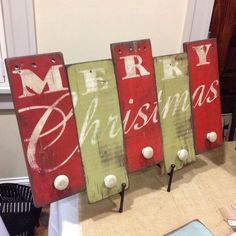 three wooden signs with merry christmas written on them in red and green, sitting on a table