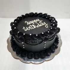 a black birthday cake with the words happy birthday written on it