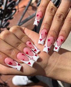 a woman's hand with pink and white hearts painted on it, holding up her nails