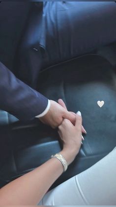 two people holding hands in the back seat of a car with a heart sticker on it