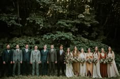 a group of people standing next to each other in front of trees