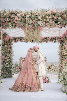 a bride and groom are standing under an archway with flowers on the side at their wedding ceremony