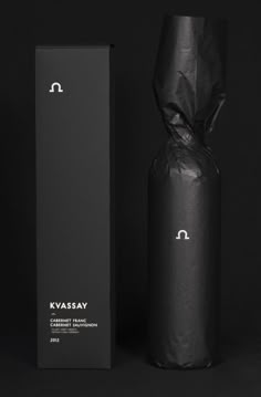 a black bottle next to a box on a black background with the word kassay printed on it