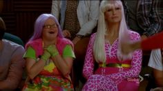 two women sitting next to each other in front of a group of people with pink hair