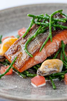 a plate with salmon, asparagus and other vegetables on the side is shown