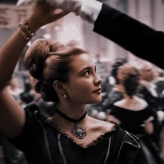 a woman getting her hair styled by a man in a tuxedo at an event