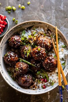 a bowl filled with meatballs and rice next to chopsticks on a table