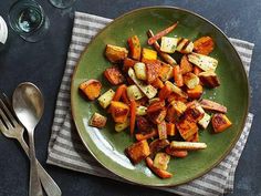 a green plate topped with cooked vegetables on top of a table next to utensils