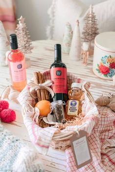 two bottles of wine sitting in a basket on a table next to other holiday decorations