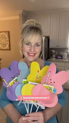 a woman is holding some paper flowers and toothbrushes in her hands while smiling at the camera