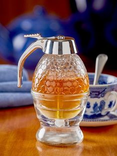 a glass pitcher with honey in it sitting on a table