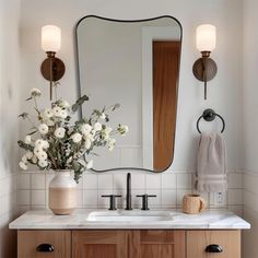 a bathroom with a sink, mirror and flowers on the counter