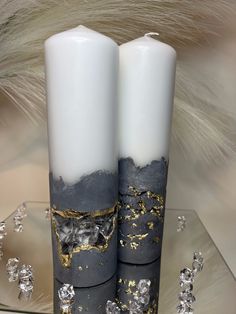 two white candles with black and gold designs on them