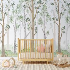 a baby's room with a wall mural that has trees on it