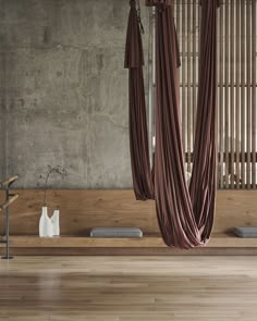 an empty room with wooden flooring and large drapes hanging from the ceiling above it