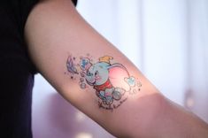 an elephant tattoo on the arm of a woman's left arm, with hearts and stars around it