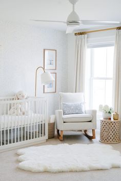 a baby's room with a white crib, rocking chair and large window