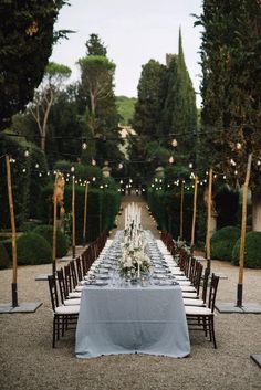 a long table with white flowers and candles is set up in the middle of an outdoor garden