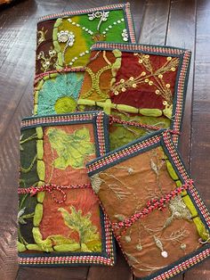 four patchwork pieces of cloth on a wooden floor with beaded trimmings