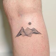 a man with a tattoo on his leg that has mountains and waves in the background