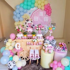 a birthday party with balloons and decorations on the floor in front of a pink barn