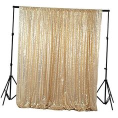 a gold sequin backdrop on a white background with two black stands and one light