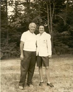 an old black and white photo of two people standing next to each other in the grass