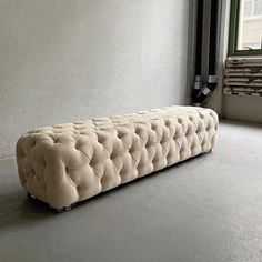 a white couch sitting on top of a cement floor next to a window in an empty room