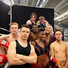 a group of people standing next to each other in a boxing ring with their arms crossed