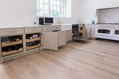 an empty kitchen with white appliances and wooden floors in the center, along with open cabinets