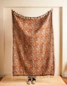 a woman standing in front of a floral tapestry